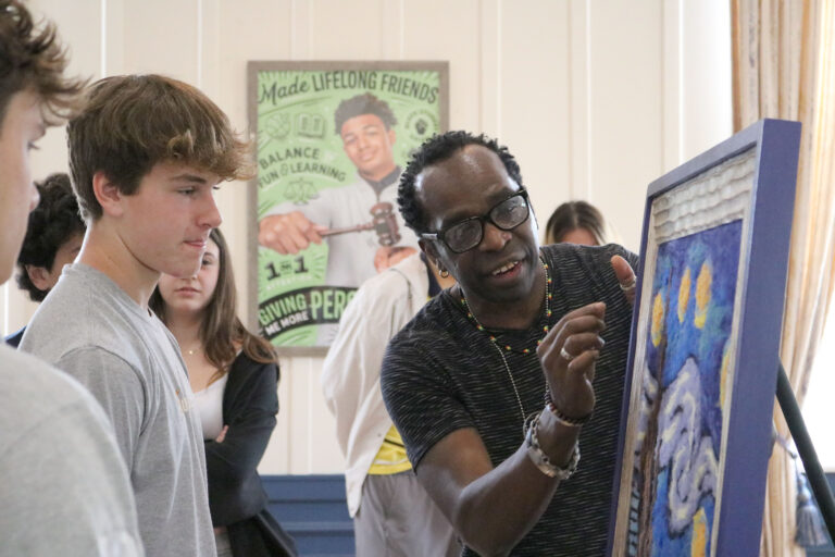 Pierre Sylvain talking to a Cheshire Academy student pointing at painting