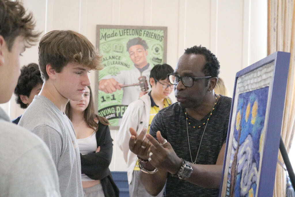 Man talking to two students facing artwork at Cheshire Academy