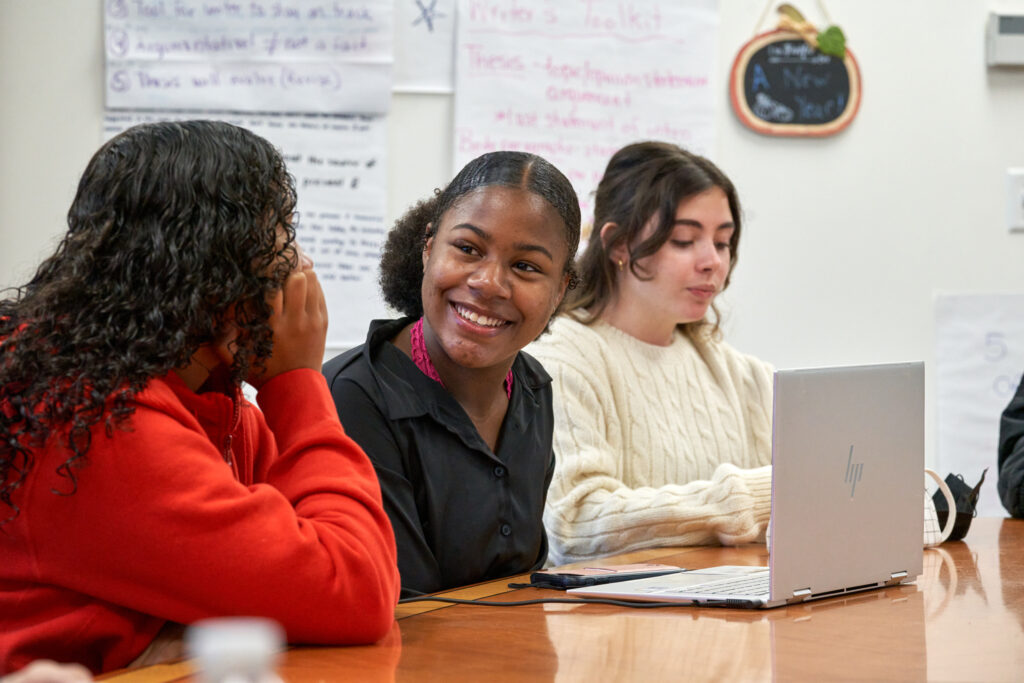 Student smiling over latop looking at another student Cheshire Academy