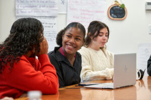 Student smiling over latop looking at another student Cheshire Academy